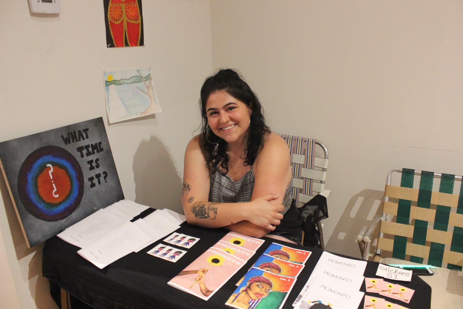 News Editor Nicole F. Anderson smiles as she shows off her artwork and sells her creative writing mini-series during an art show on Aug. 21.