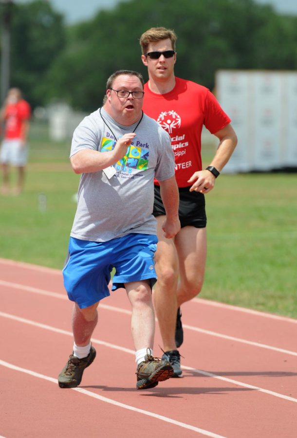 A participant and a volunteer running in a Special Olympics race.