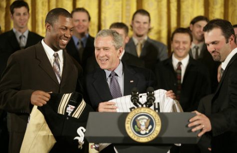 President George W. Bush is presented with a Chicago White Sox jacket and baseball jersey, Monday, Feb. 13, 2006 by White Sox players Jermaine Dye, left, and Paul Konerko in the East Room of the White House, where President Bush honored the 2005 World Series Champions. White House Photo by Eric Draper)