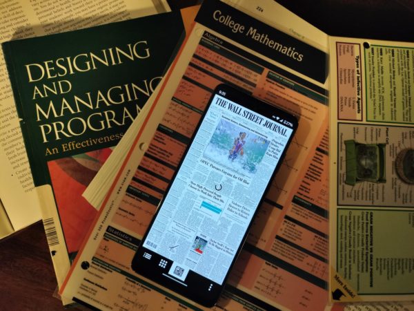 The WSJ Print Edition app is featured on an Android phone on top of school work.