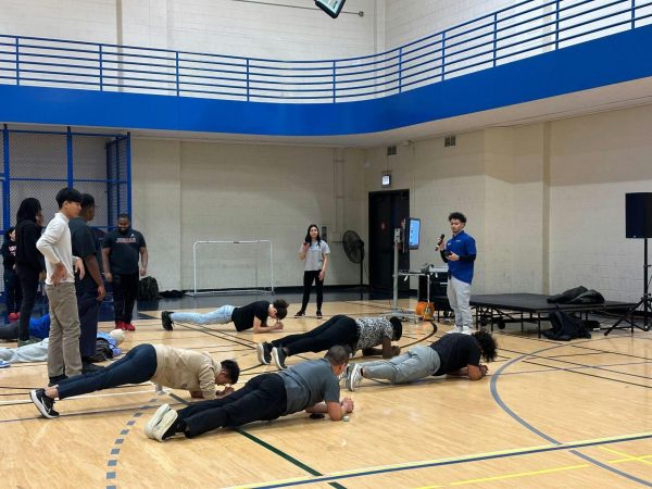 A planking activity is being done by event attendees in the auxiliary gym. 