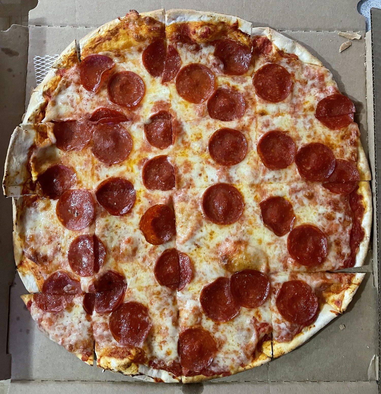 Round Pizza with square slice cuts for pizza.  Round pepperoni piece are main topping.