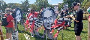 Participates in the Coalition to March on DNC hold the black and white cutouts of US Vice President Kamala Harris and Russia President Vladimir Putin with red streamers connected to their hands to convey the funding of genocide.