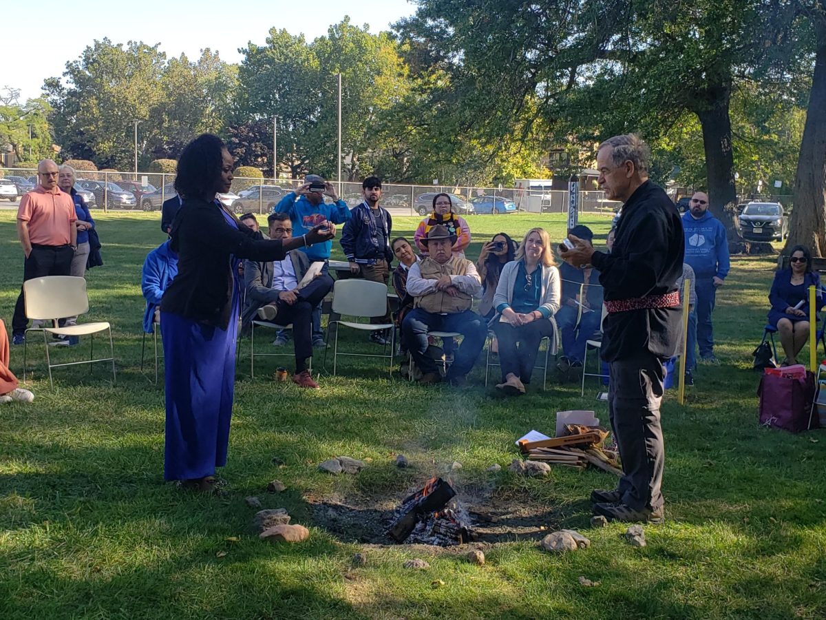 President Dr. Katrina Bell Jordan reaching over the fire for the peace stick